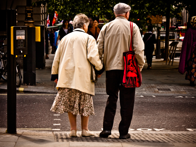 An elderly couple crosses the street hand in hand. Photo by garryknight. 