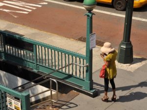 A passenger on a mobile phone entering the New York City subway. Photo by momentcaptured1/Flickr.